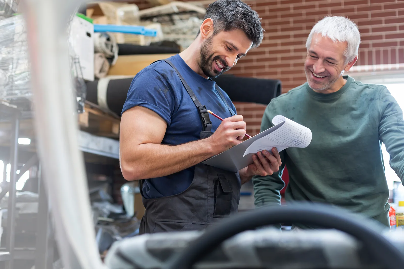 Friendly staff reviewing insurance claim documents with a customer in the repair shop